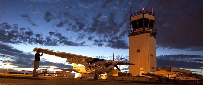 Small plane parked in front of a County airport tower.