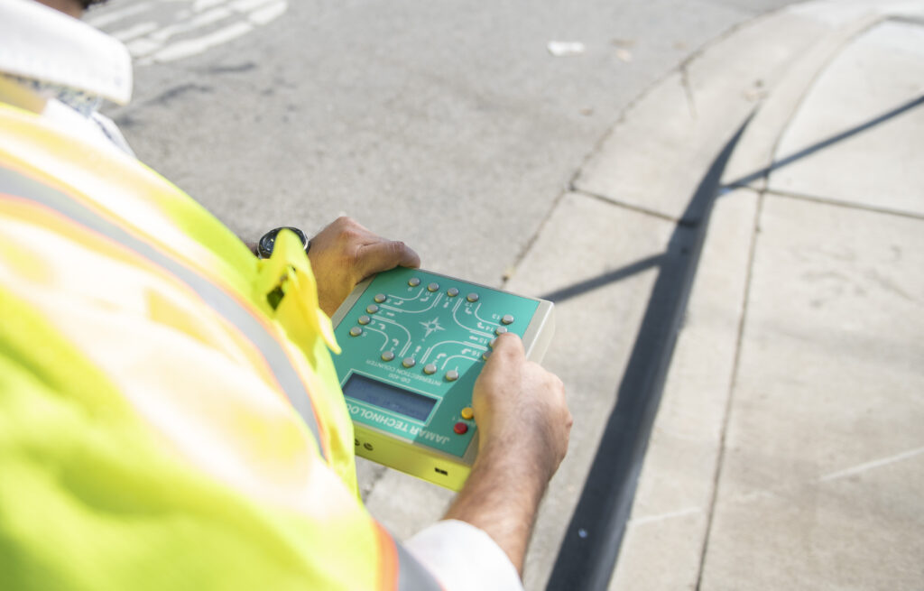 Field employee in the street with a technical device in hand.